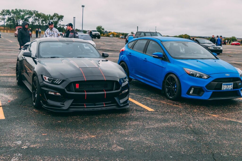 Black GT350 and blue Focus RS parked with spectators in the background.